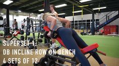 a woman doing squats on a bench in a gym with other people working out