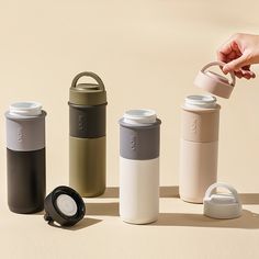 thermos are lined up in different colors and sizes, including one with a lid