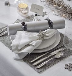 the table is set with silver and white place settings, napkins, and glasses