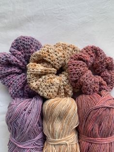 several skeins of yarn in various colors on a white background, including pink, beige and purple