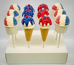 four ice cream cones with red, white and blue toppings in them on sticks