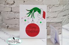 a christmas card with an ornament hanging from it's side next to a brick wall