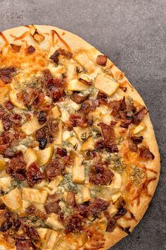 a pizza sitting on top of a pan covered in cheese and toppings with bacon