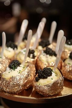 small desserts with spoons sticking out of them sitting on a gold platter