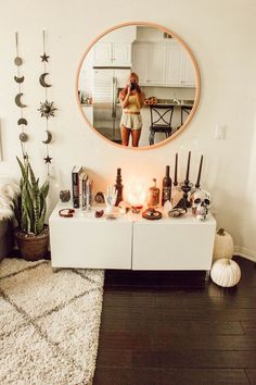 a woman standing in front of a mirror with candles on the table and other decorations