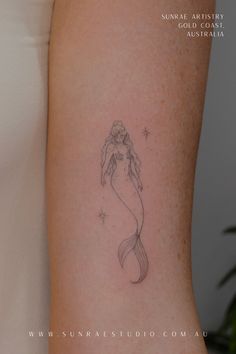 a small mermaid tattoo on the arm