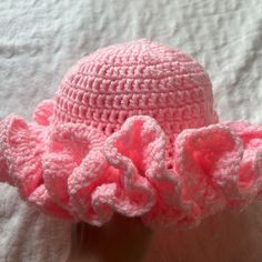 a pink crocheted hat with ruffles on the brim