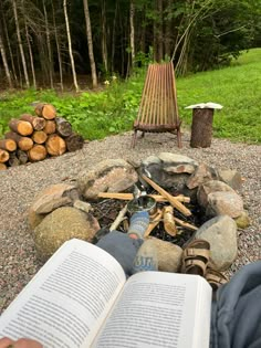 an open book sitting on top of a pile of rocks next to a fire pit