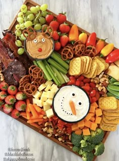 a platter with fruit, vegetables and crackers in the shape of a snowman