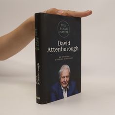 a hand holding a book about david attenbrough, with the cover open