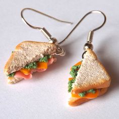 a pair of sandwich shaped earrings hanging from silver earwires on a white surface