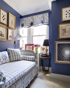 a living room with blue walls and pictures on the wall above the couch is shown