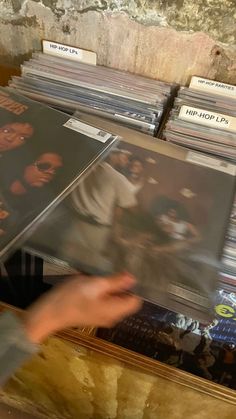 a person reaching for records in a record store with the album's labels on them