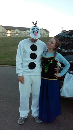 a man and woman in costumes standing next to a car with a frozen queen costume on