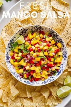 a bowl filled with mango salsa surrounded by tortilla chips