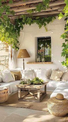 an outdoor living room with white furniture and wicker baskets on the floor, covered in greenery