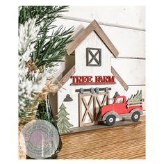 a red truck is parked in front of a white barn with a tree farm sign