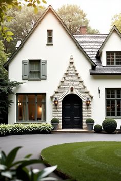 a white house with black shutters and green grass in front of the entrance to it