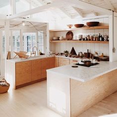 an open kitchen with wooden cabinets and white counter tops is pictured in this image, there are bowls on the shelves