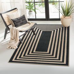 a black and white area rug in front of a window with potted plants on it