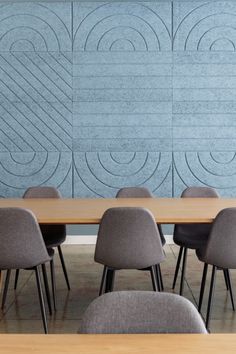 an empty conference table with chairs in front of a wall that has wavy designs on it