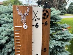 two wooden signs with numbers and deer heads on them in front of some trees outside