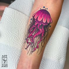 a woman's arm with a pink jellyfish tattoo on it