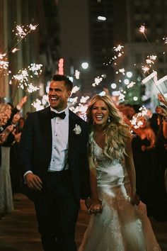 a newly married couple walking down the street with sparklers in the air behind them