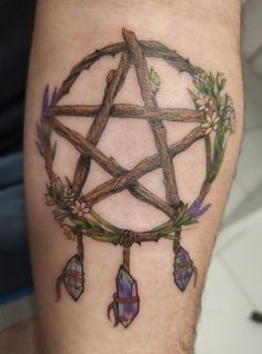 a man's leg with a pentagramil and flowers tattoo design on it