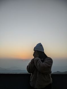 a woman standing on top of a hill looking at the sky