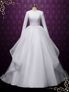 a white wedding dress with long sleeves on a mannequin head stand in front of a purple wall