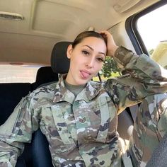 a woman in uniform sitting in the back seat of a car with her hand on her head