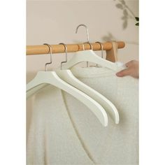 three white hangers are hanging on a wooden rail