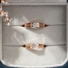 two wedding rings sitting in a box on top of a white carpeted floor next to each other