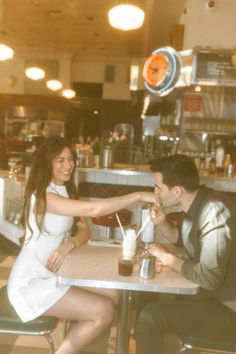 two people sitting at a table in a restaurant, one holding the other's hand