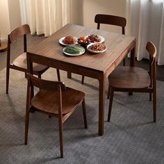 two plates of food sit on a wooden table in front of a curtained window