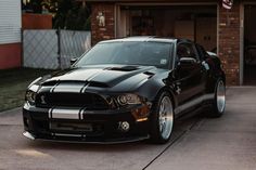 a black mustang parked in front of a garage