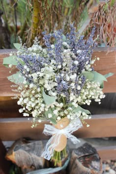 a bouquet of flowers sitting on top of a wooden bench in front of some logs