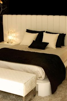 a white bed with black and white pillows on top of it's headboard