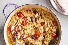 a pot filled with rice and vegetables on top of a white counter next to a spoon