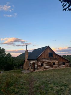 an old log cabin sits in the middle of a field