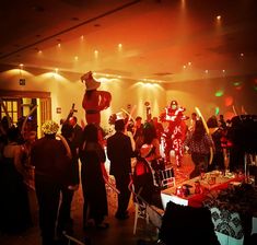 a group of people standing around a room filled with tables covered in food and decorations