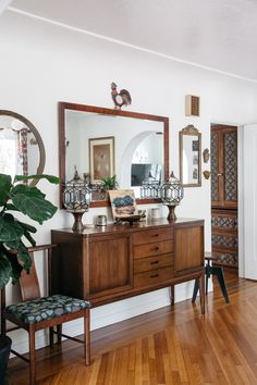 a living room with wooden floors and a large mirror on the wall above a dresser