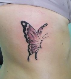 a butterfly tattoo on the back of a woman's lower body, it is pink and black