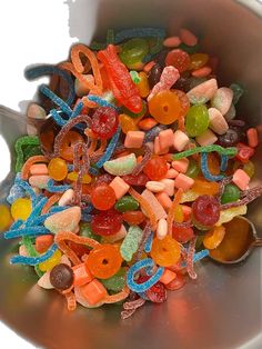 a bowl filled with lots of gummy bears and jelly beans next to a spoon