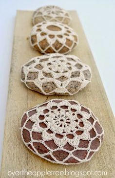 three crocheted rocks sitting on top of a wooden board with white doily