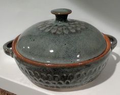 a ceramic covered dish sitting on top of a white countertop next to a rug