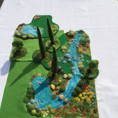 the table is covered with green and blue felted items, including trees and rocks