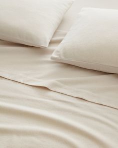 a bed with white sheets and pillows on it