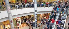 an indoor mall filled with lots of people walking around and on escalator platforms